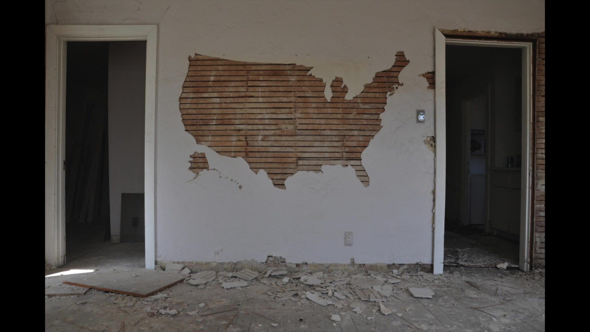 Admission Order: the shape of the United States cut out of the plaster of a wall in an abandoned house