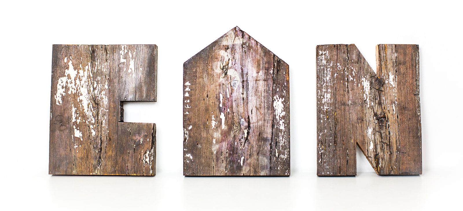 CAN: three letters, C, a house-shaped A and N, made from weathered salvaged wood