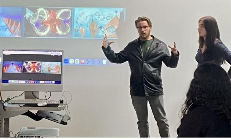 Miguel leading a critique in front of projected student work