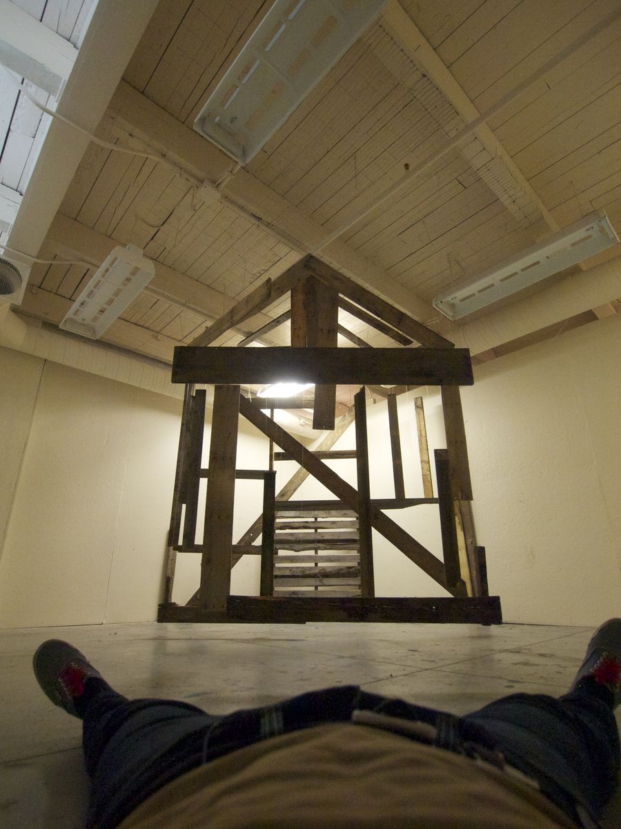 MesoToPenta: suspended wood fragments seen from the floor, aligned into the frame of a house